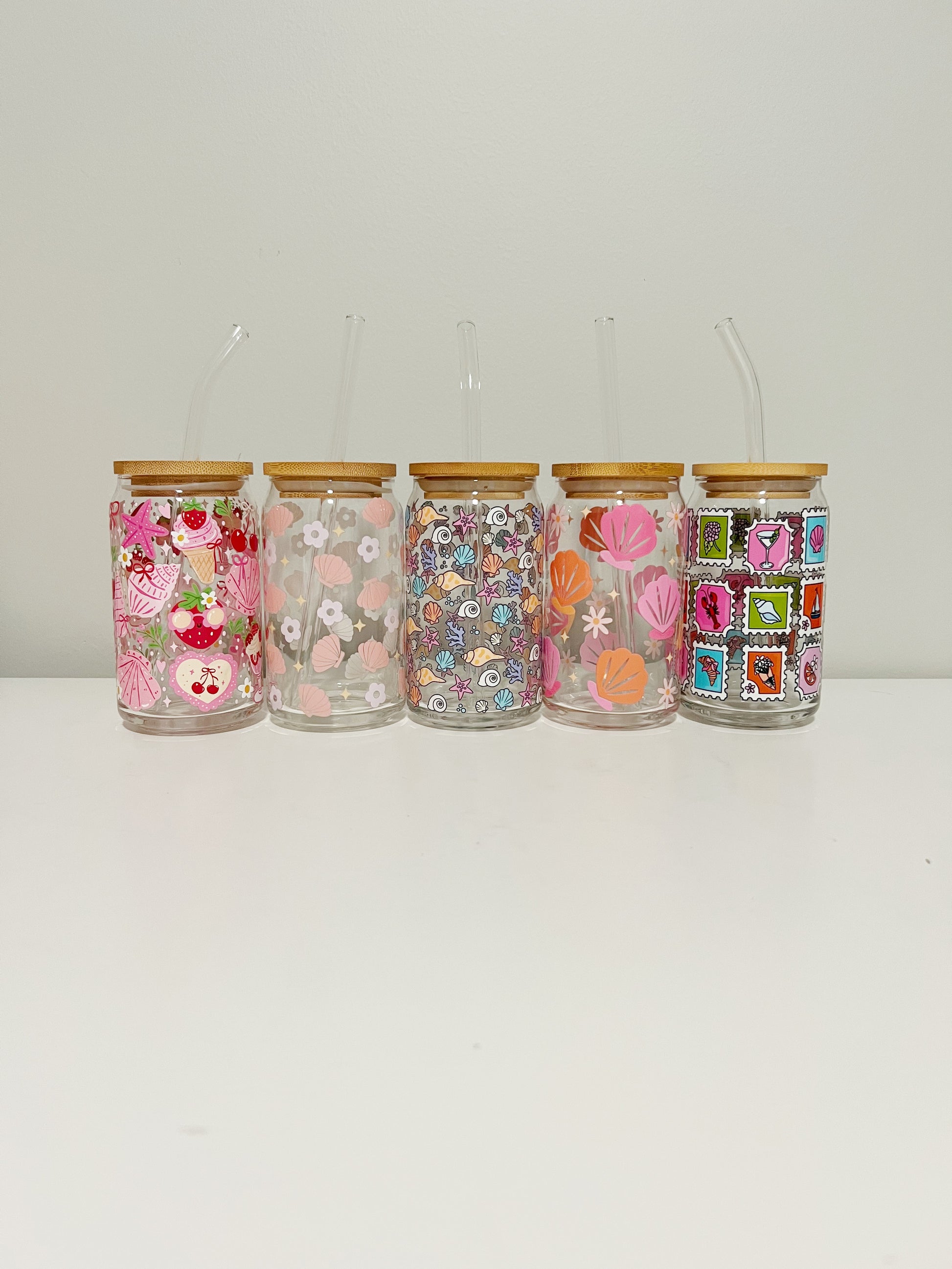 Set of five decorative glass jars with floral and patchwork designs on a white background